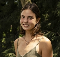 Student smiling in front of greenery