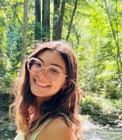 Student smiling surrounded by trees